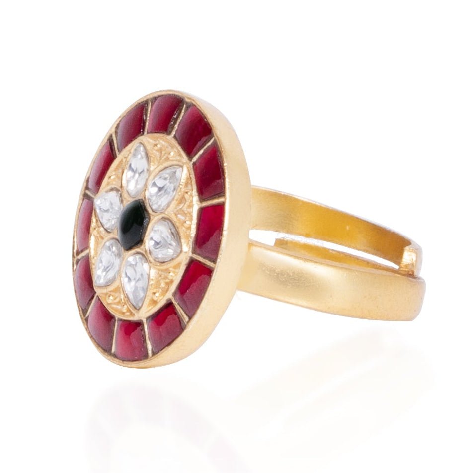 Gold ring with a red stone and black center on a white background