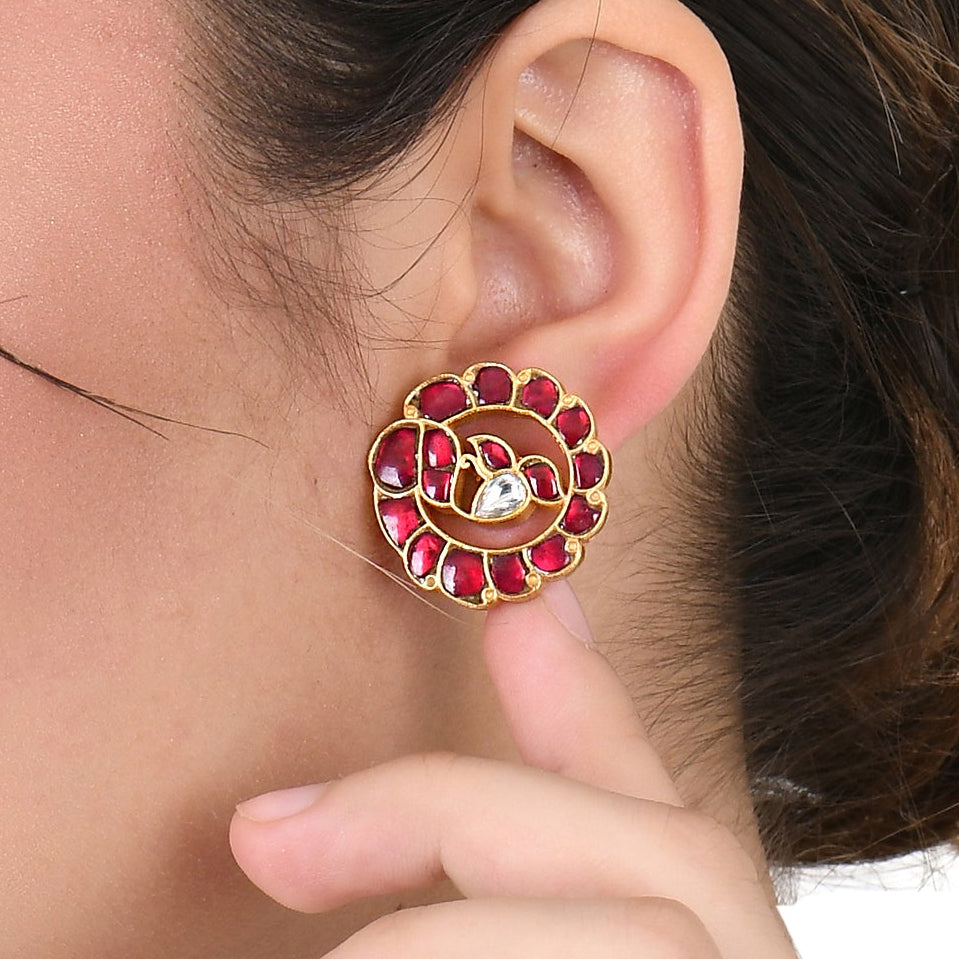 Woman wearing a red and gold earring on a white background