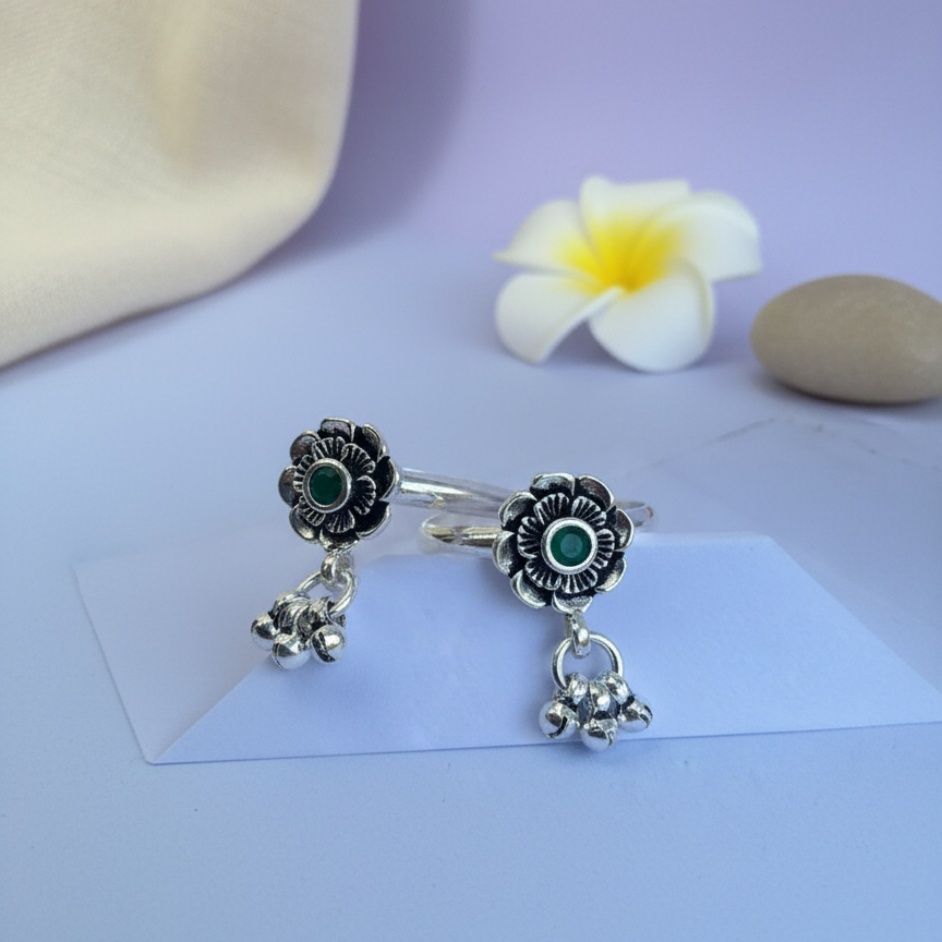 Silver rings with floral designs on a light purple surface with a flower and stone.