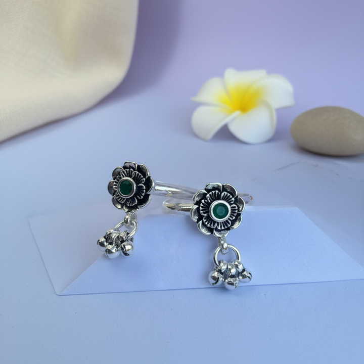 Silver rings with floral designs on a light purple surface with a flower and stone.