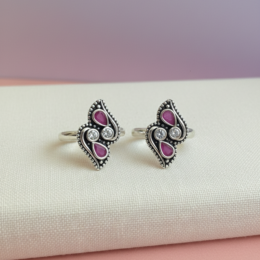 Pair of silver rings with pink gemstones on a white surface