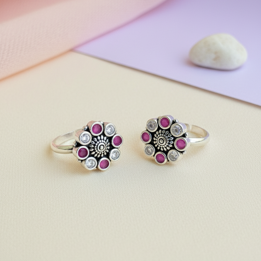 Two silver rings with pink gemstones on a light background