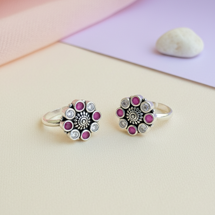 Two silver rings with pink gemstones on a light background