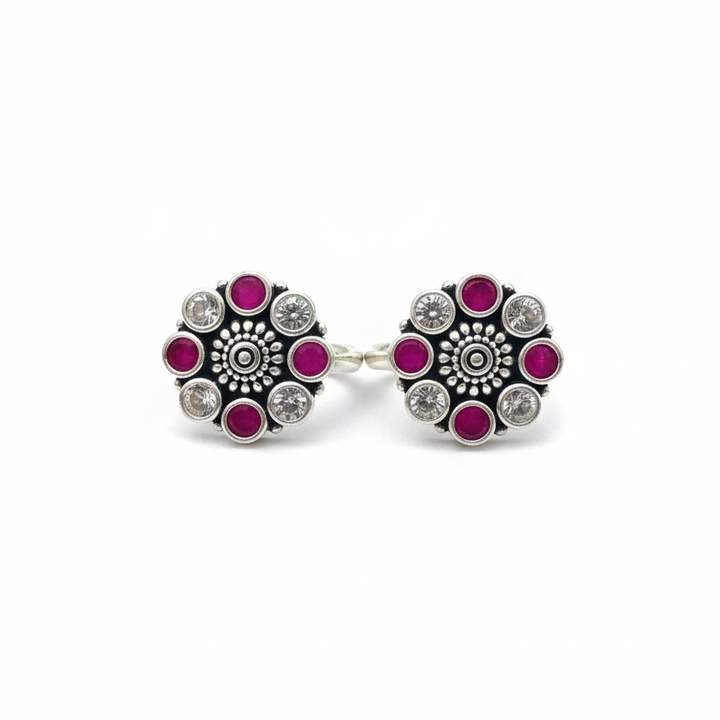 Pair of earrings with floral design and pink gemstones on a white background