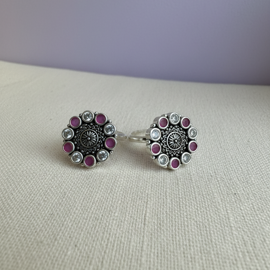 Pair of silver earrings with purple gemstones on a light gray surface.