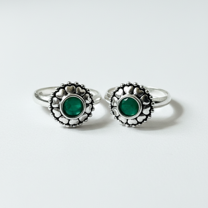 Pair of silver rings with green gemstones on a white background