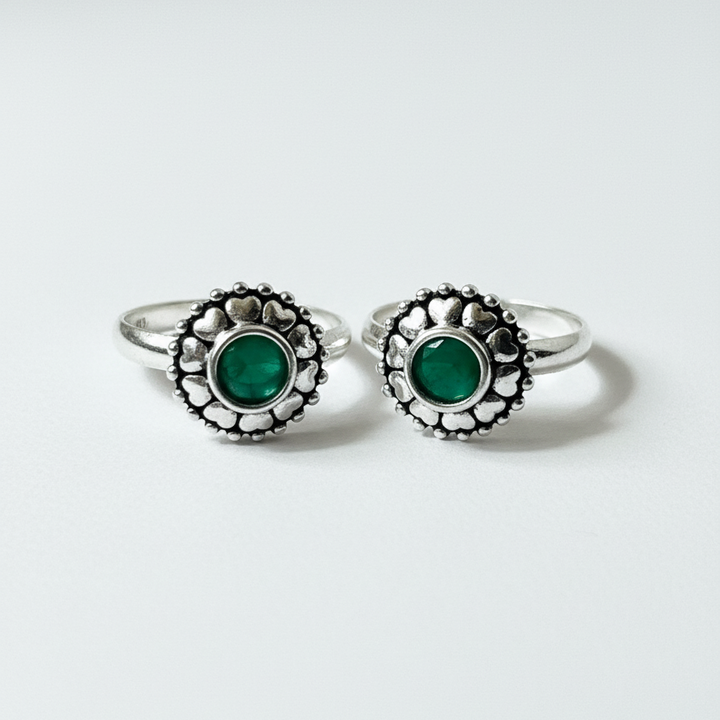 Pair of silver rings with green gemstones on a white background