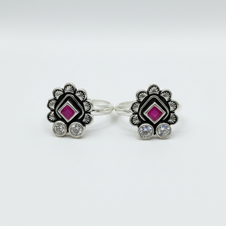 Pair of earrings with a central pink gemstone and silver accents on a white background