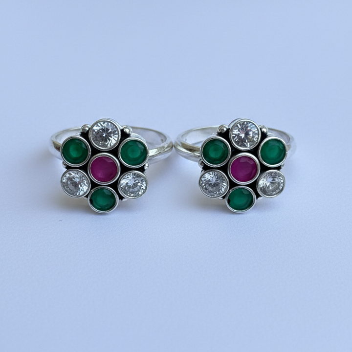 Pair of earrings with green and pink gemstones on a white background