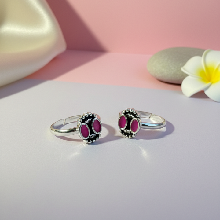 Two silver rings with pink gemstones on a light pink background